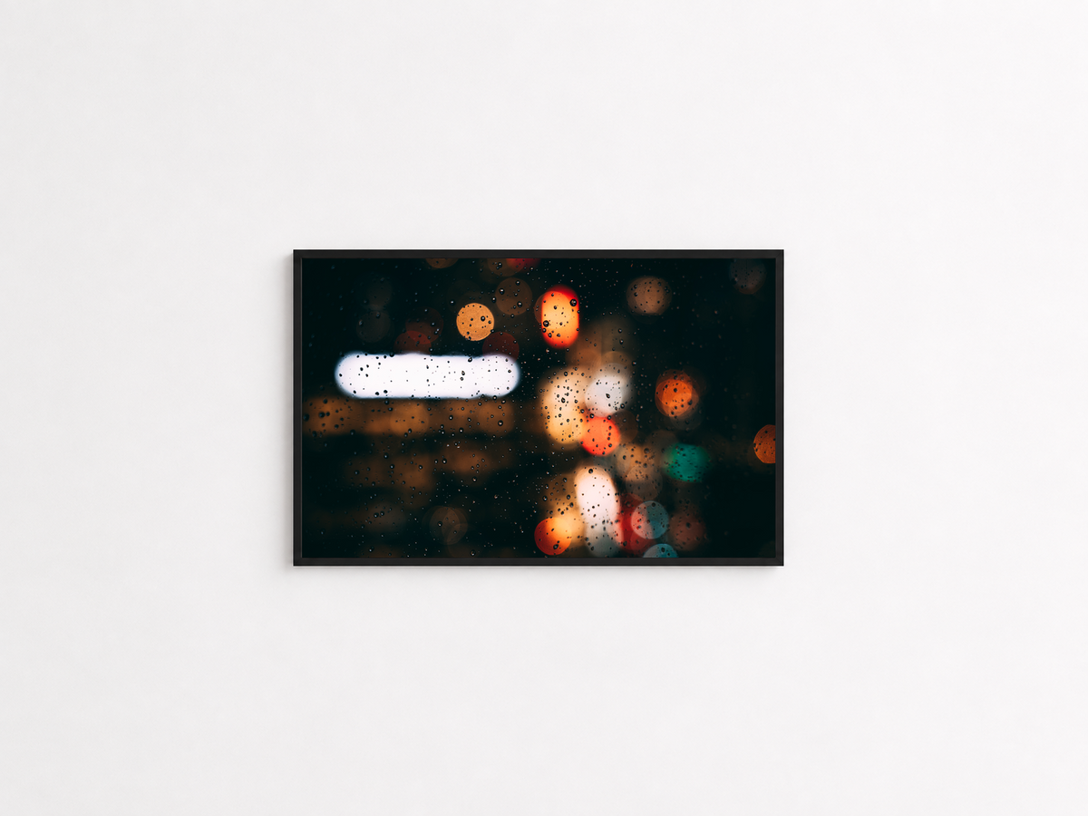 Rain droplets and blurred city lights photography print in a black frame